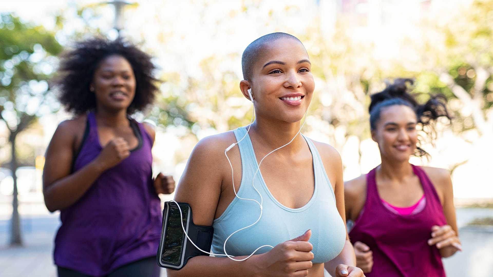Three happy women jogging in the park